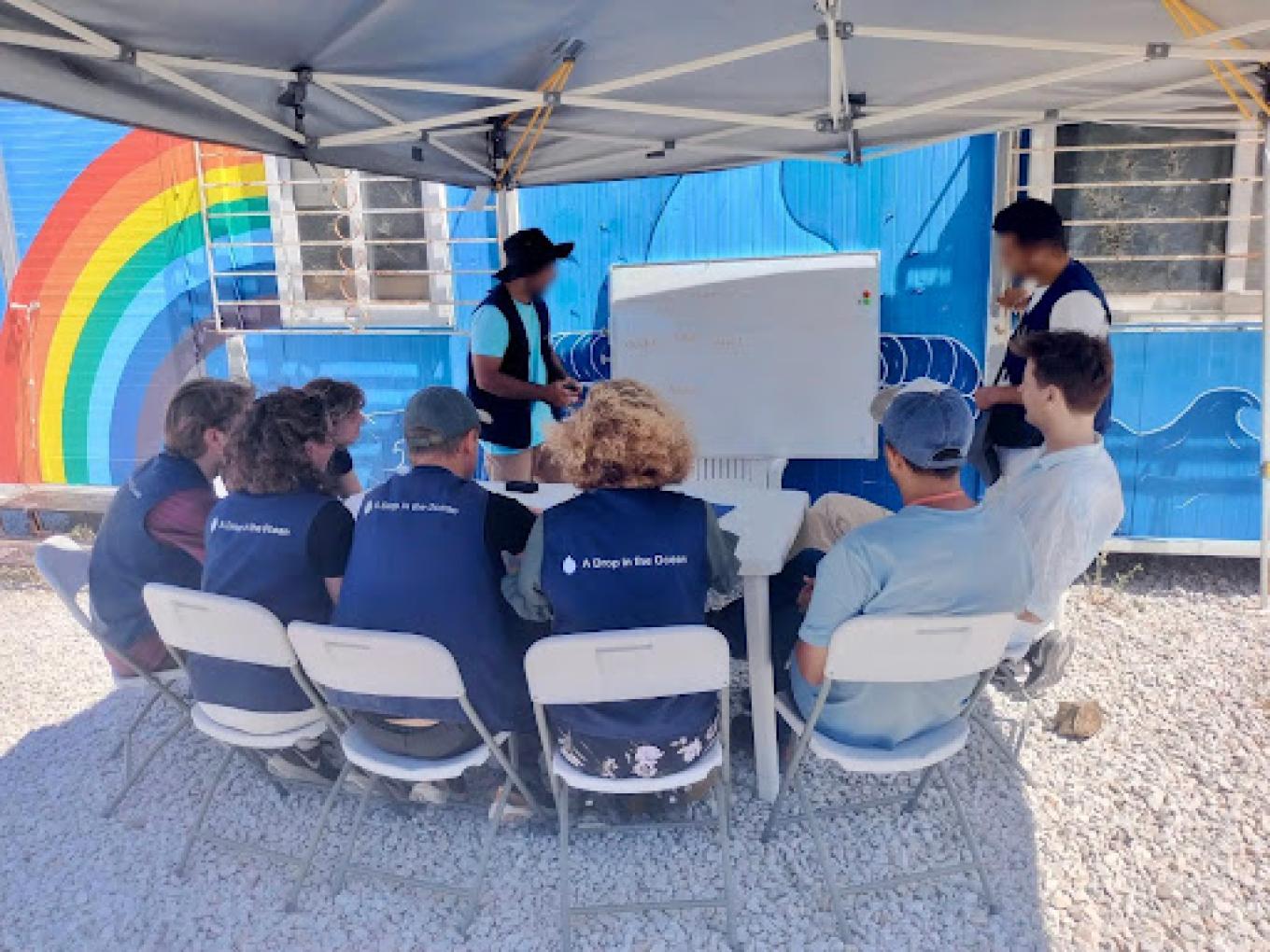 Observing a Farsi class for international volunteers, taught by refugees who are camp residents and volunteers for A Drop in the Ocean